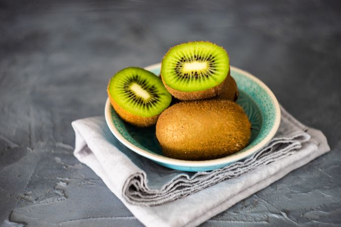 Bowl of kiwi fruits with one halved on top