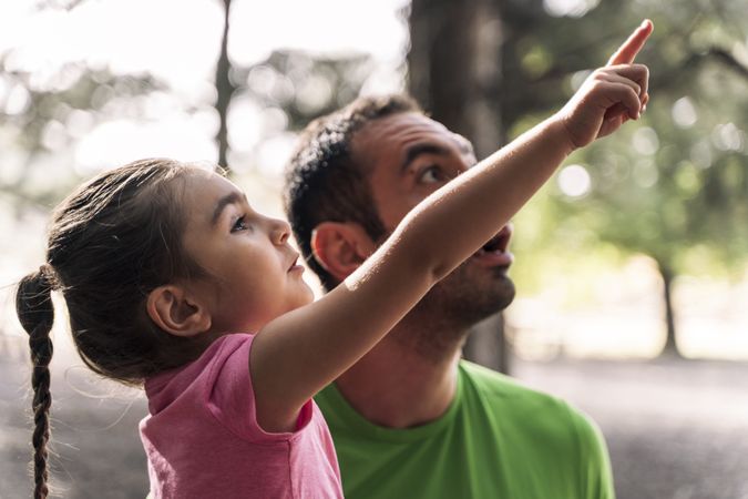 Young daughter pointing something out to her father, a moment of discovery in a forest.