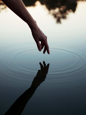 Person touching body of water with reflection