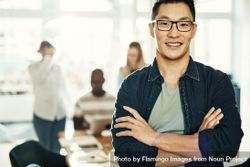 Portrait of Asian man smiling with arms crossed in bright office bEzdl0