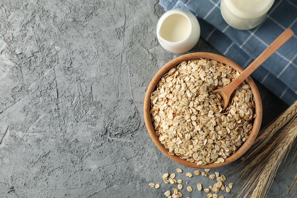 Composition with oatmeal flakes on gray background. Cooking breakfast