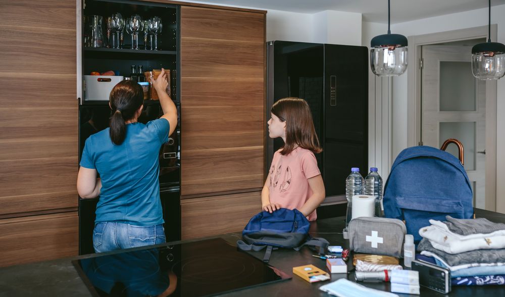 Mother preparing emergency backpack with her daughter