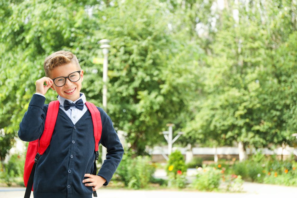 Boy in school uniform against greenery background, space for text