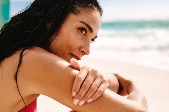 Close up of beautiful woman sitting on the beach and looking away