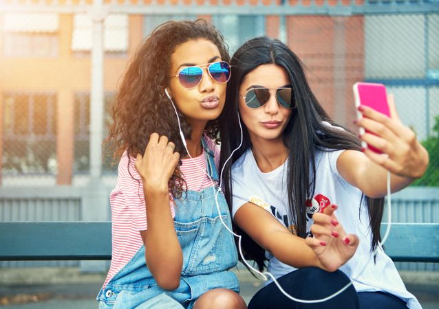 Two female adults posing for selfie on smart phone