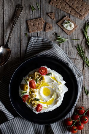Crackers and herbs near plate with labneh