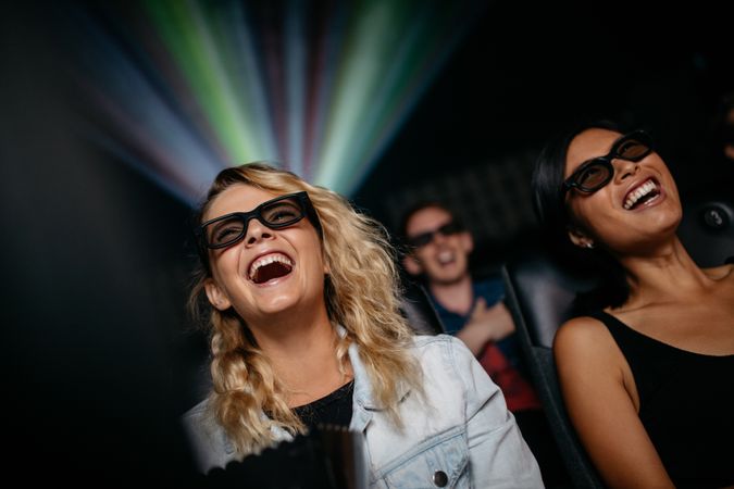 Smiling female friends watching 3d movie in theater