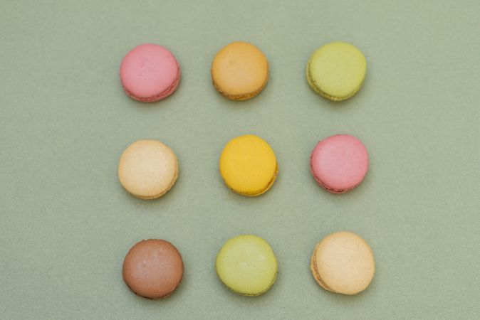 Nine macaroons on green table from above
