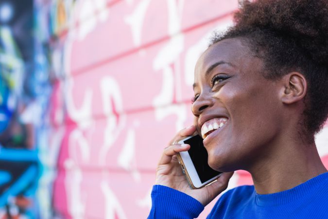 Content Black woman speaking on smartphone in city