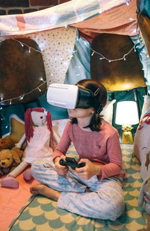 Girl wearing virtual reality headset and playing games sitting over mats in tent
