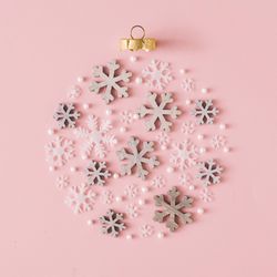 Snowflakes making shape of holiday decoration on pink background
