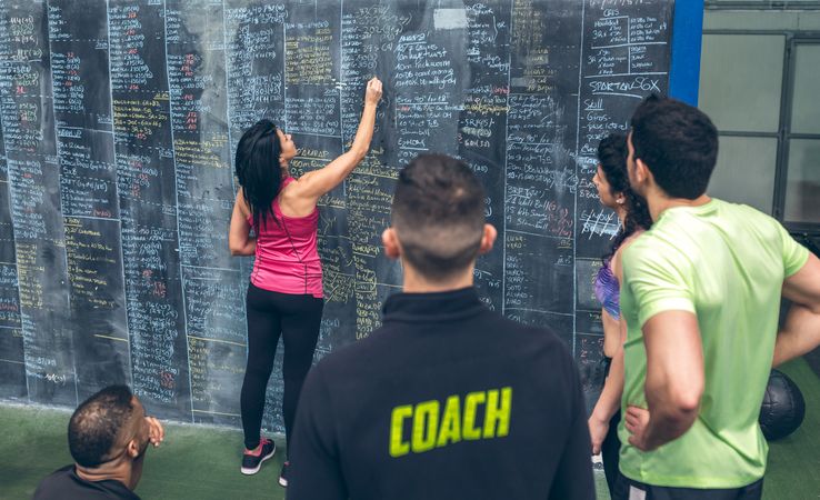 Athlete woman writing down results on the gym board