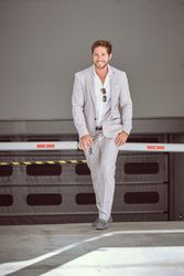 Confident businessman in suit walking against white fence