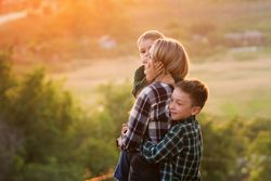 Happy mother and sons at sunset together in field