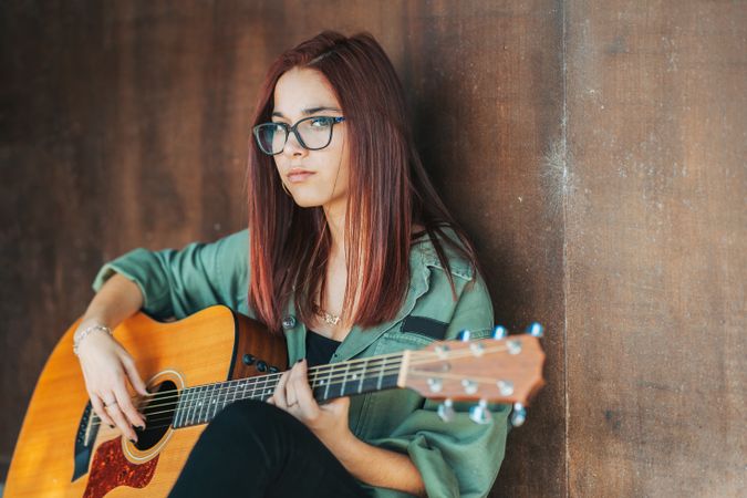 Romantic woman playing guitar leaning on wall