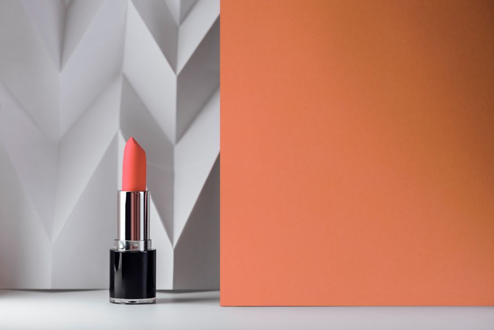 Living coral color lipstick on soft pink chevron background and copy space for text