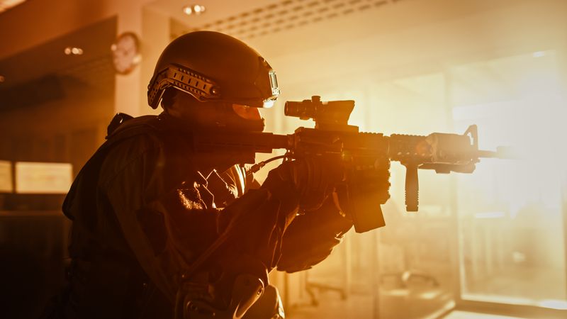 Close Up Portrait of Masked Squad Member of Armed SWAT Police Officers Who Storm a Dark Seized Office Building with Desks and Computers