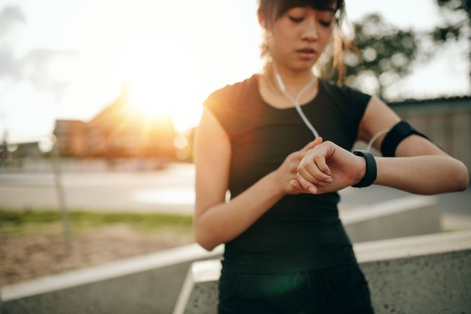 Close up shot of young woman jogger ready to run looking at smartwatch