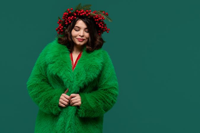 Elegant woman in green coat and red berry wreath