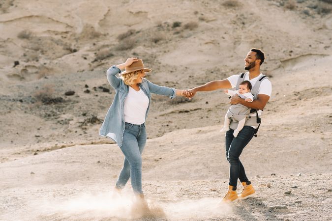 Diverse parents dancing while walking with baby