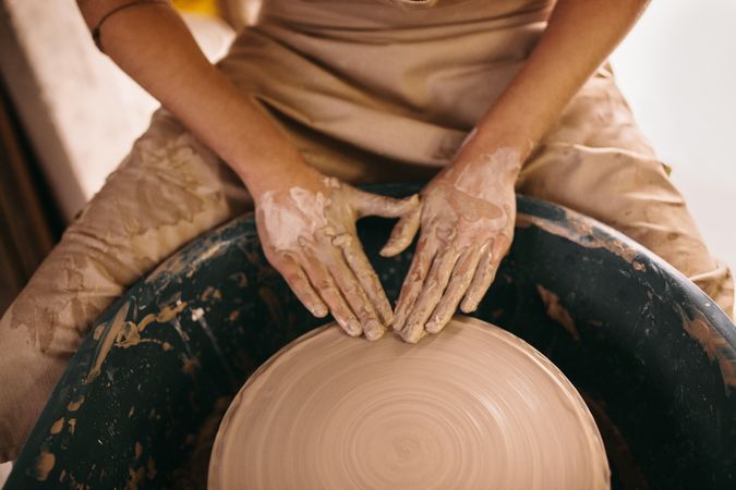 Potter moulding clay on pottery wheel in studio