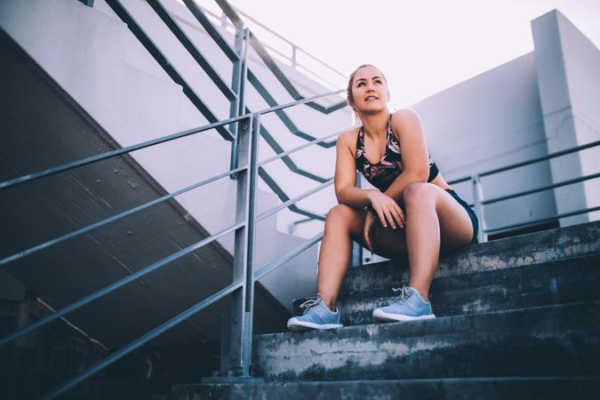 Young woman sitting on stadium stairs looking in the distance