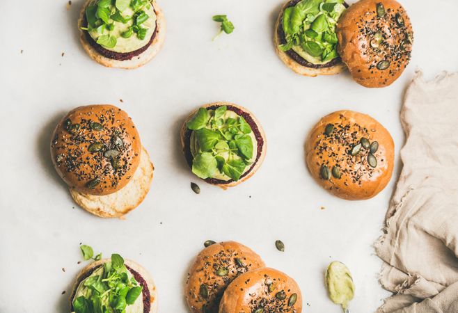 Fresh vegan burgers on seeded buns arranged on light background