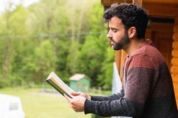 Thoughtful man reading book on terrace of house