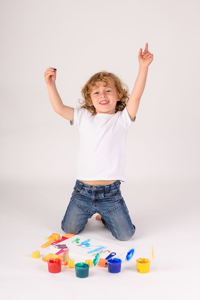 Excited boy near colorful paints