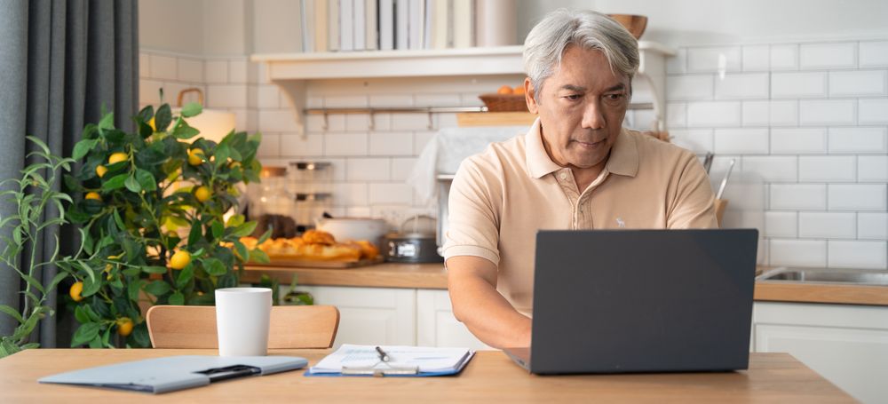 Asian mature man learning or working with laptop in the morning at home