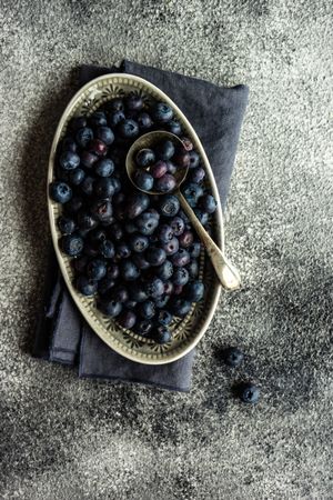 Top view of blueberries in dish with spoon and copy space