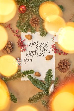 Christmas greeting written with a beautiful handmade letter with Christmas decorations and lights around.