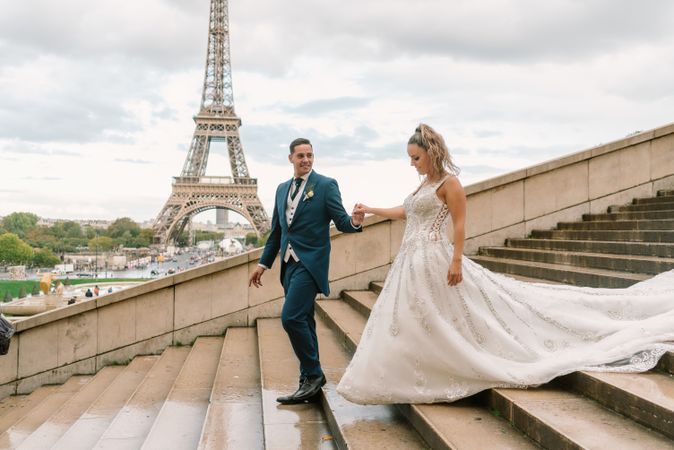 Happy newlyweds walking downstairs holding hands in Paris