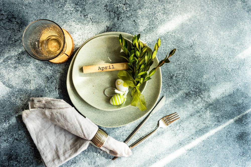 Easter concept with branch and green decorative eggs on ceramic plates with copy space