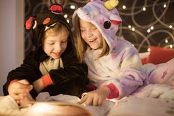 Kids reading Christmas fairy tales in bed