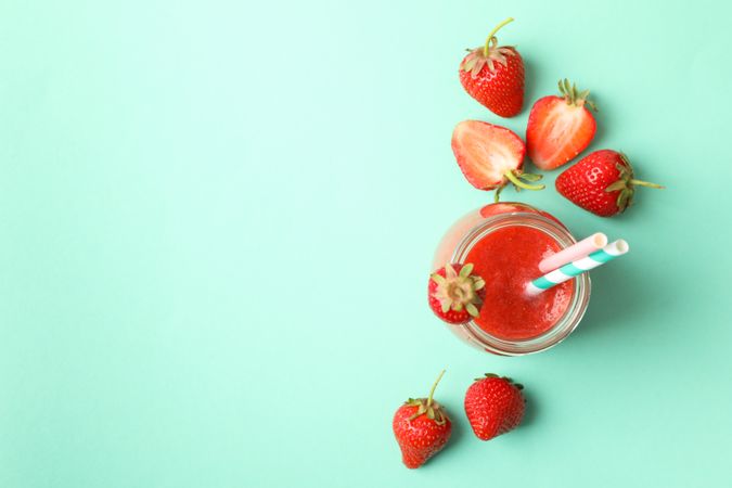 Glass jar with strawberry cocktail on mint background. Summer drink