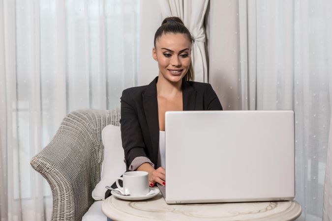 Smiling businesswoman working on her laptop in hotel room