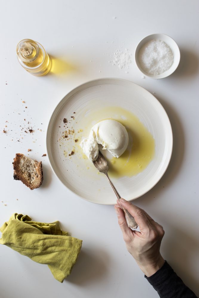 Crop hand taking cheese near bread and oil