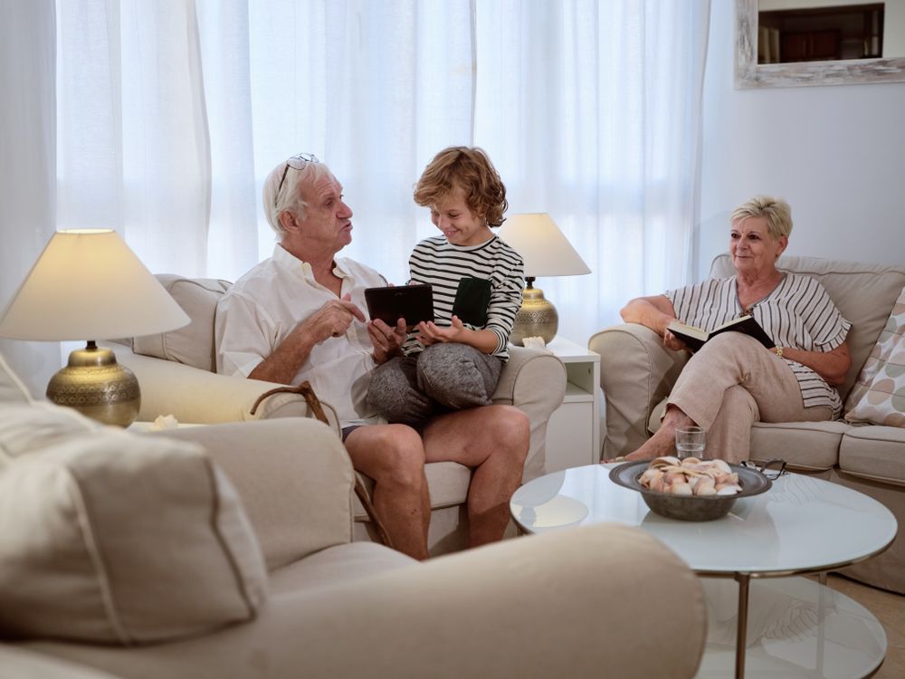 Boy browsing tablet with grandfather on couch