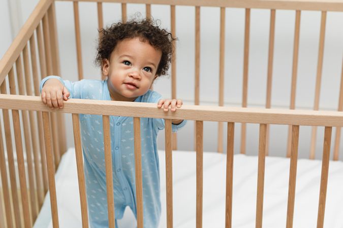 Curious baby boy standing in crib