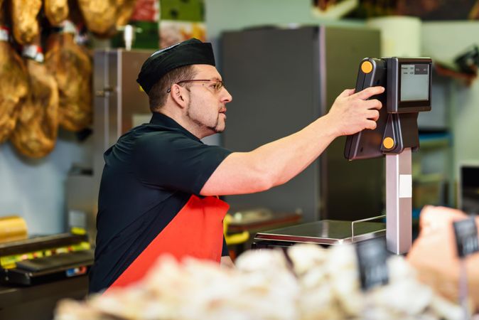 Man in butcher shop serving a customer at register