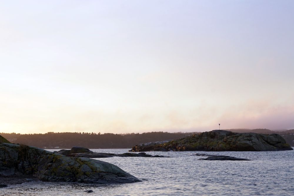 Rocky shore of tranquil sea in dusk