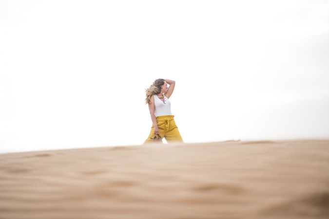 Happy woman holding shoes in desert