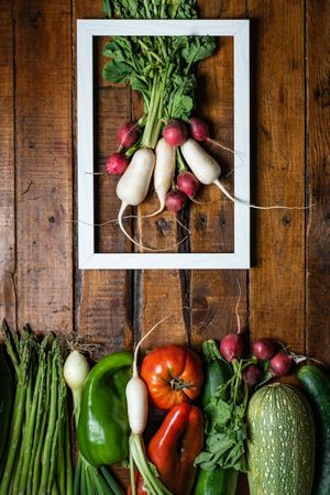 Composition with vegetables and white frame in wooden table