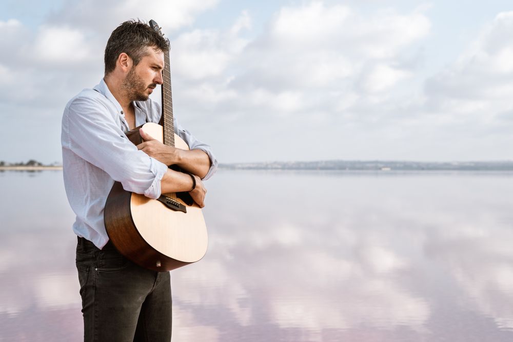 Inspired musician embracing guitar at seaside