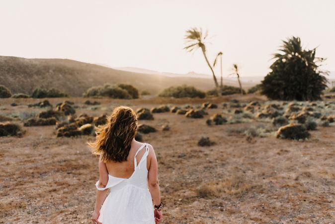 Woman in white dress in dry field in sunlight