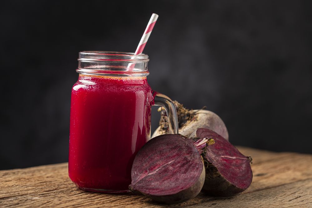 Red beet juice in a glass cup on the wooden table.