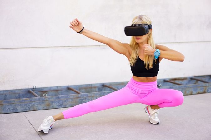 Strong sportswoman practicing martial arts in VR headset
