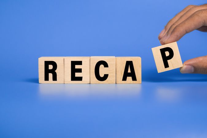recap word text on wooden blocks isolated on blue background