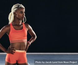 Female athlete standing on track on a dark background beN9P0